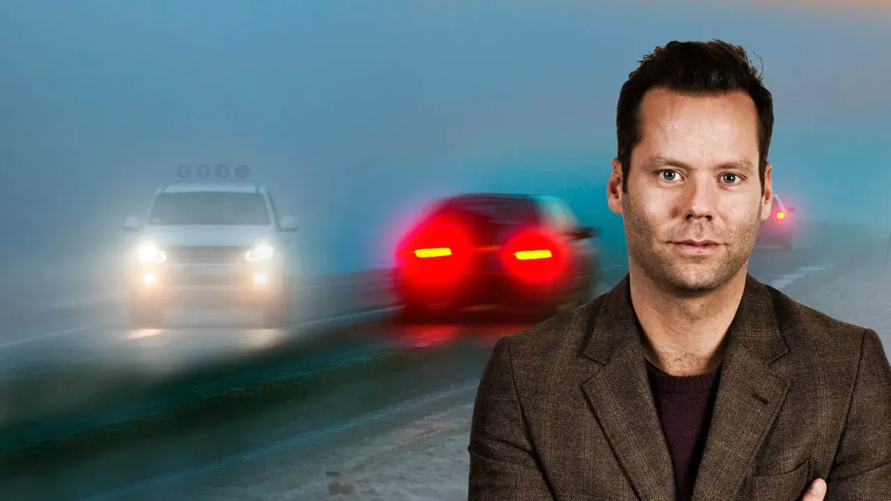 Man i kostym framför dimmig väg med bilar. Viktigt med dimljus regler för säkerhet.