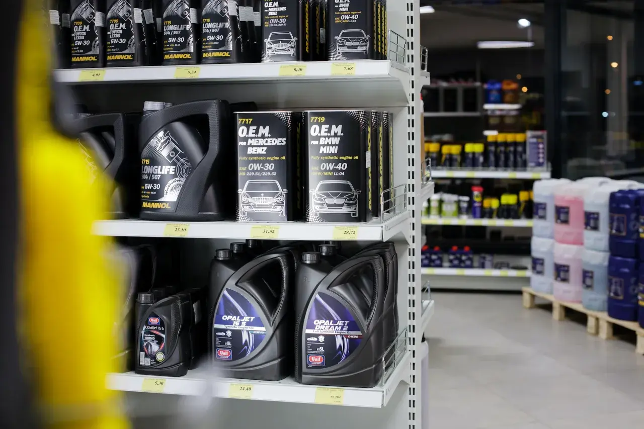 Hyllor fyllda med motoroljor, inklusive helsyntetisk olja för olika bilmärken.