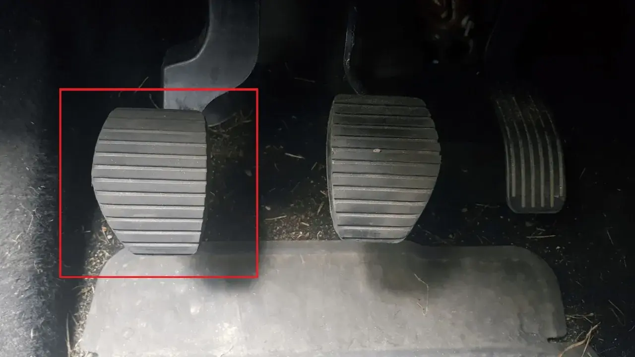 Kopplingspedalen i en manuell bil, markerad med röd ram. Denna pedal är avgörande för att växla.