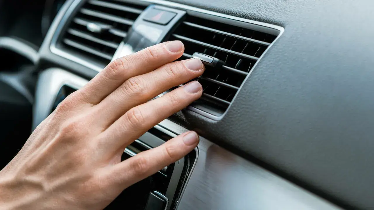 Hand justerar luftkonditionering bil för behaglig temperatur.