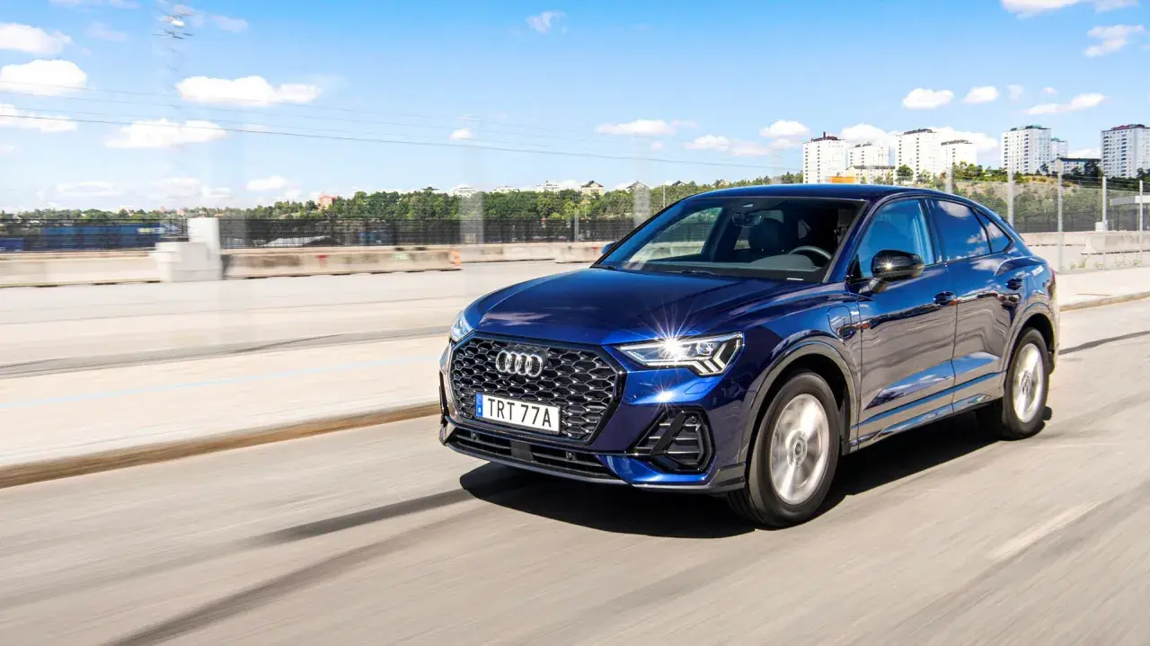 Mörkblå Audi Q3 kör på en motorväg i Sverige. Inga problem med denna bil, bara en härlig dag.