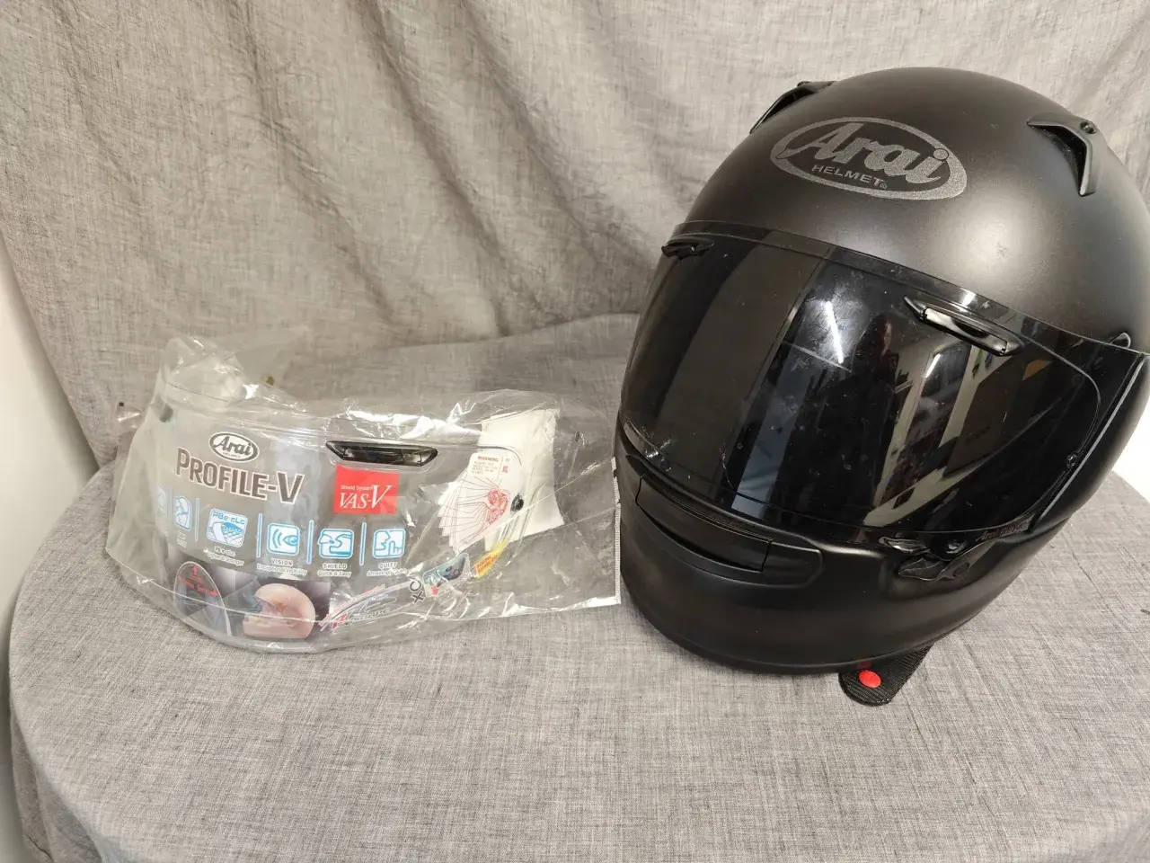 Svart Arai Profile-V hjälm med visir i förpackning. Perfekt för dig som söker en säker och bekväm hjälm.