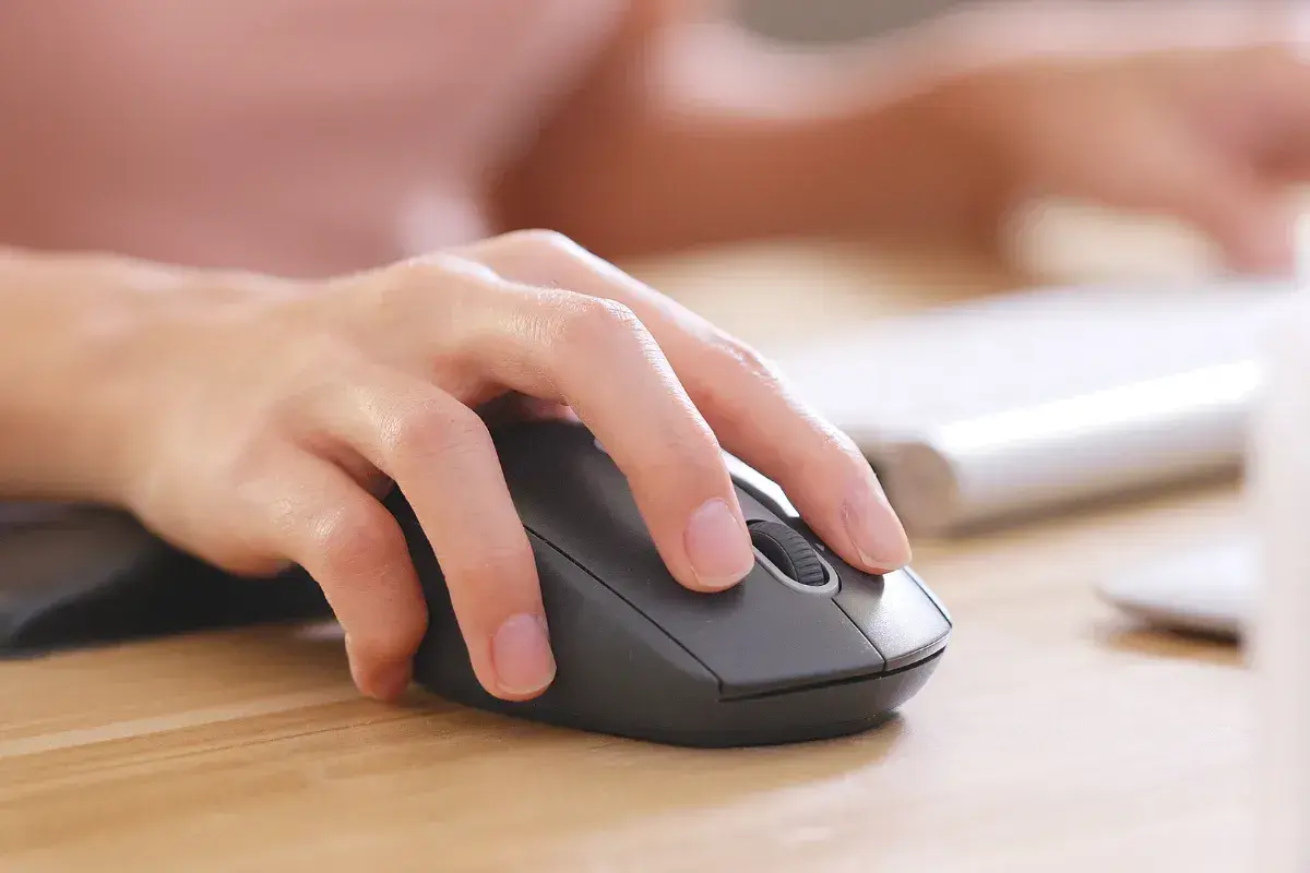En hand använder en datormus. Kanske letar personen efter information om vad kostar teoriprov.