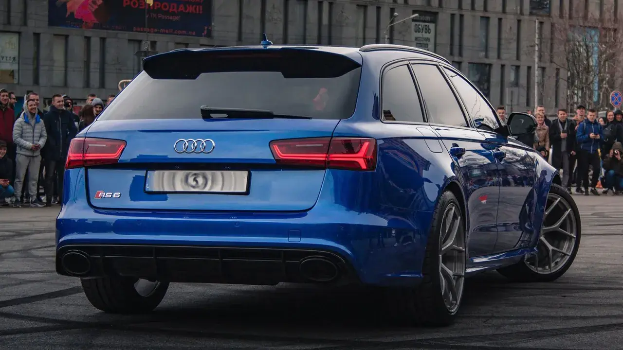 Blue Audi RS6 Avant with a crowd watching.