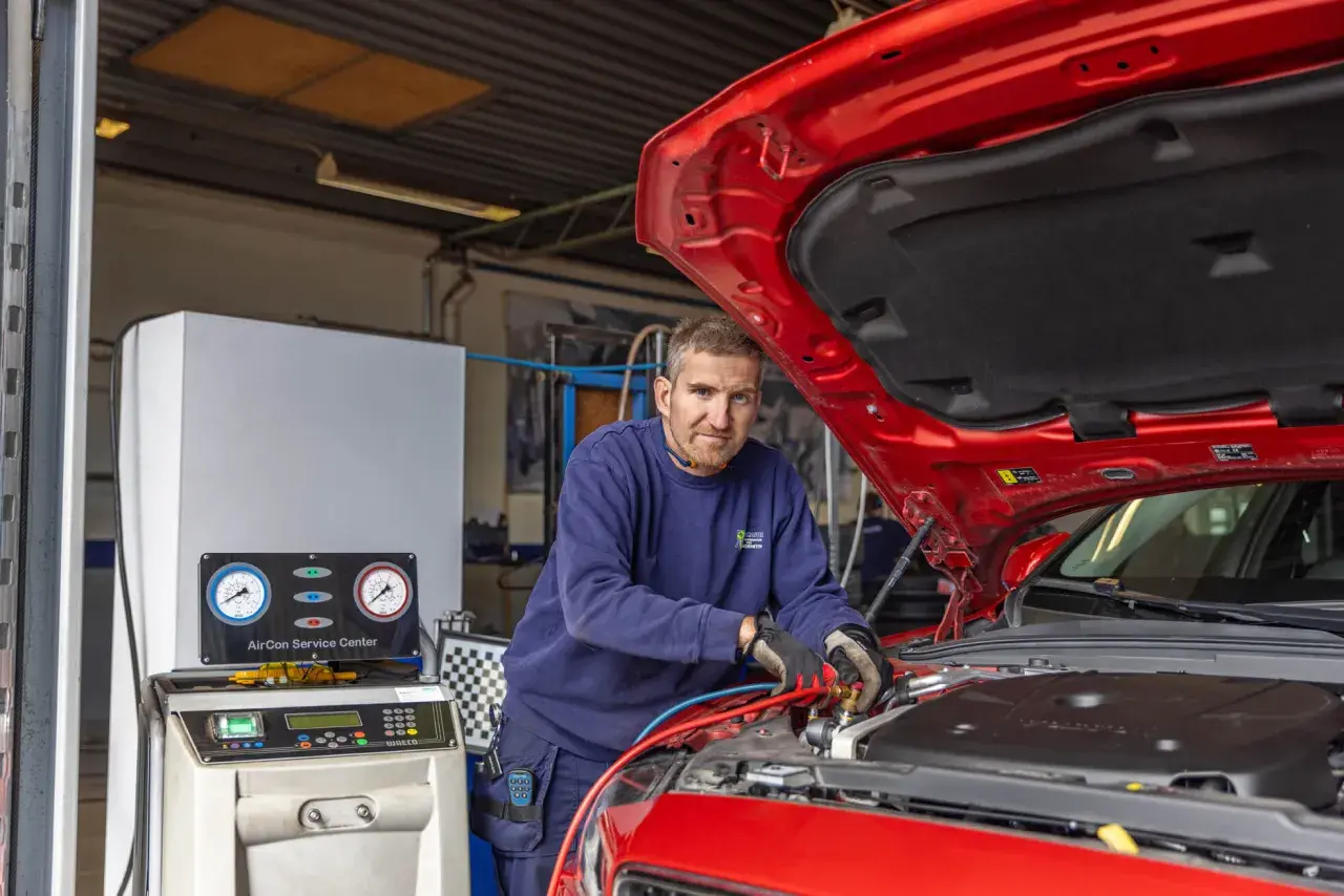 Mekaniker arbetar med bilens AC-system. En maskin med tryckmätare visar hur fungerar ac i bilen.