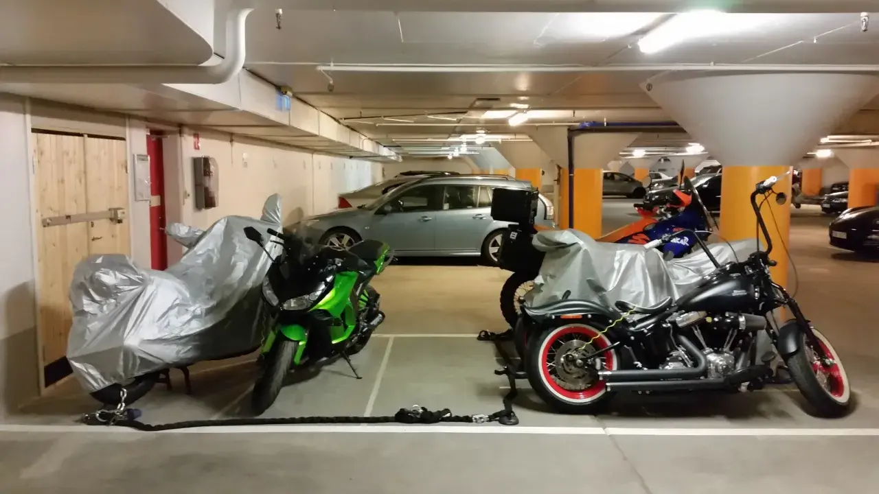 Här parkerar du moped klass 1: två motorcyklar, en grön och en svart, står i ett garage.