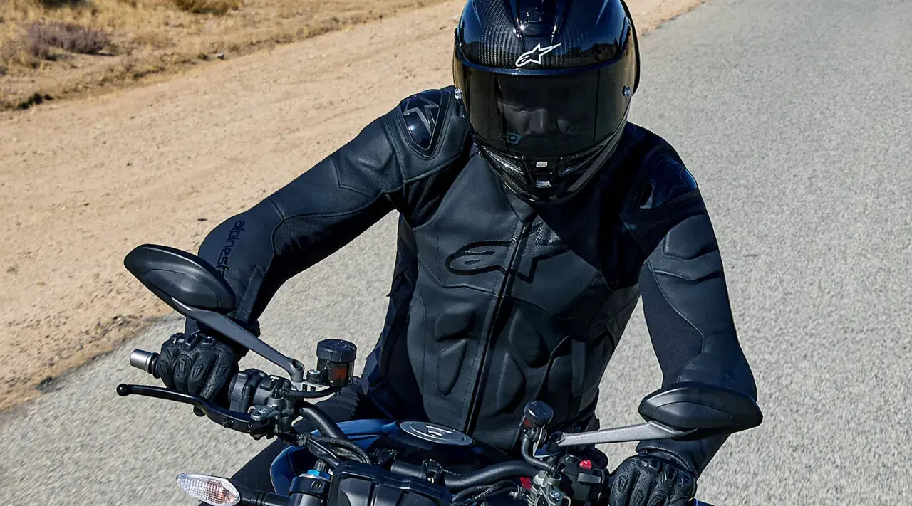 Motorcyklist i en Alpinestars skinnjacka, redo för äventyr på en öppen väg.