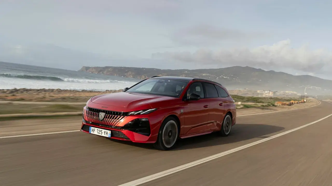 Röd Peugeot 308 kombi kör längs en kustväg. Inga problem med denna bil, bara en vacker vy.