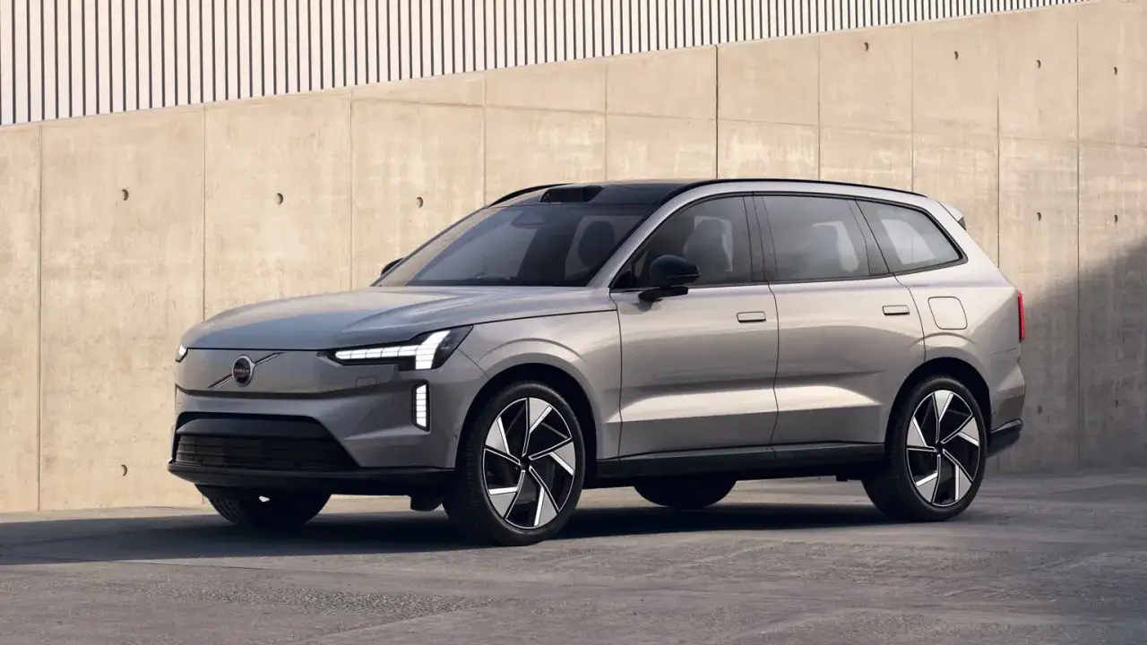 Silver elbil 7 sits med modern design, parkerad framf&ouml;r en betongv&auml;gg med vertikala linjer.
