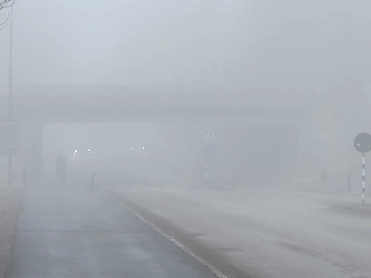Tung dimma gör det svårt att se. En cyklist syns i fjärran. Tänk på dimljus regler för säkerhet.