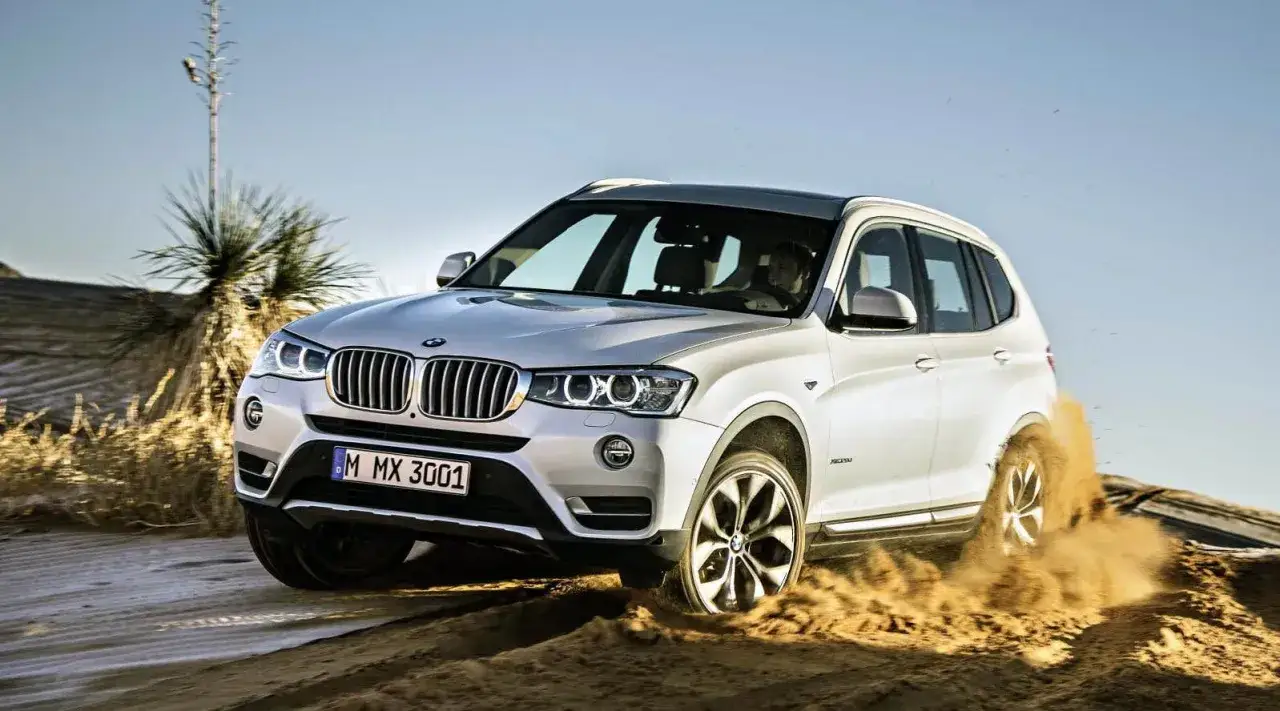 Vit BMW X3 kör i sanden, hjulen slirar. Ett potentiellt BMW X3 problem med greppet i terrängen.