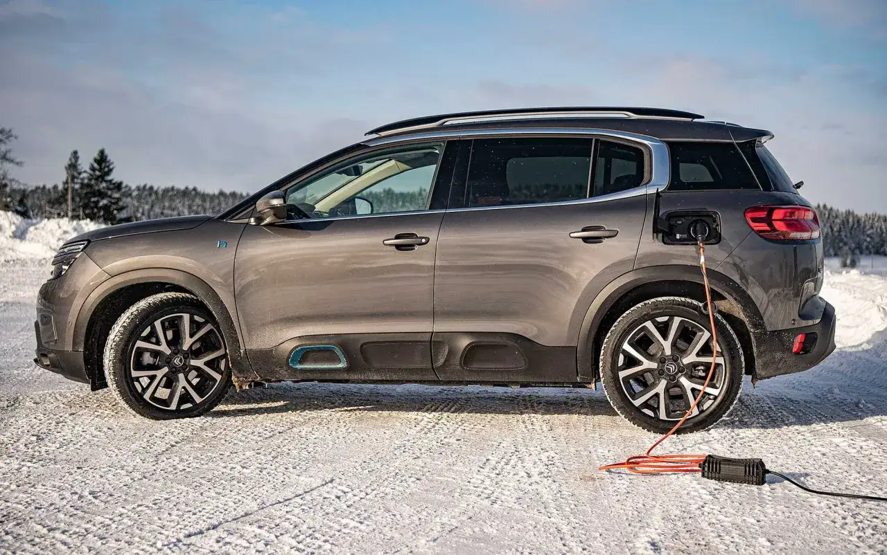 Grå Citroën C5 Aircross laddas i snö. Ett problem kan vara att batteriet laddas långsamt i kyla.