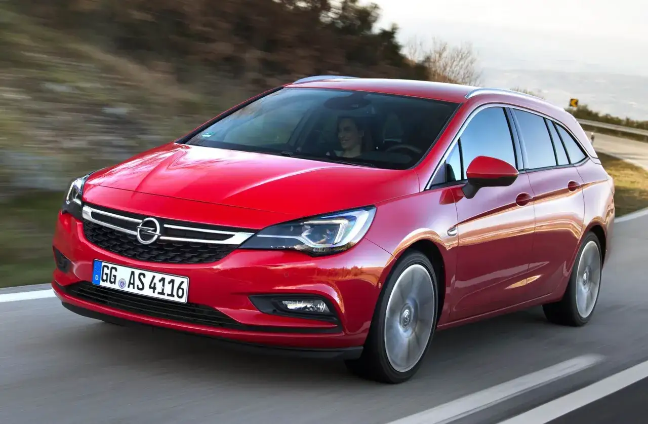 Röd Opel Astra Sports Tourer kör på en landsväg. En kvinna kör bilen.