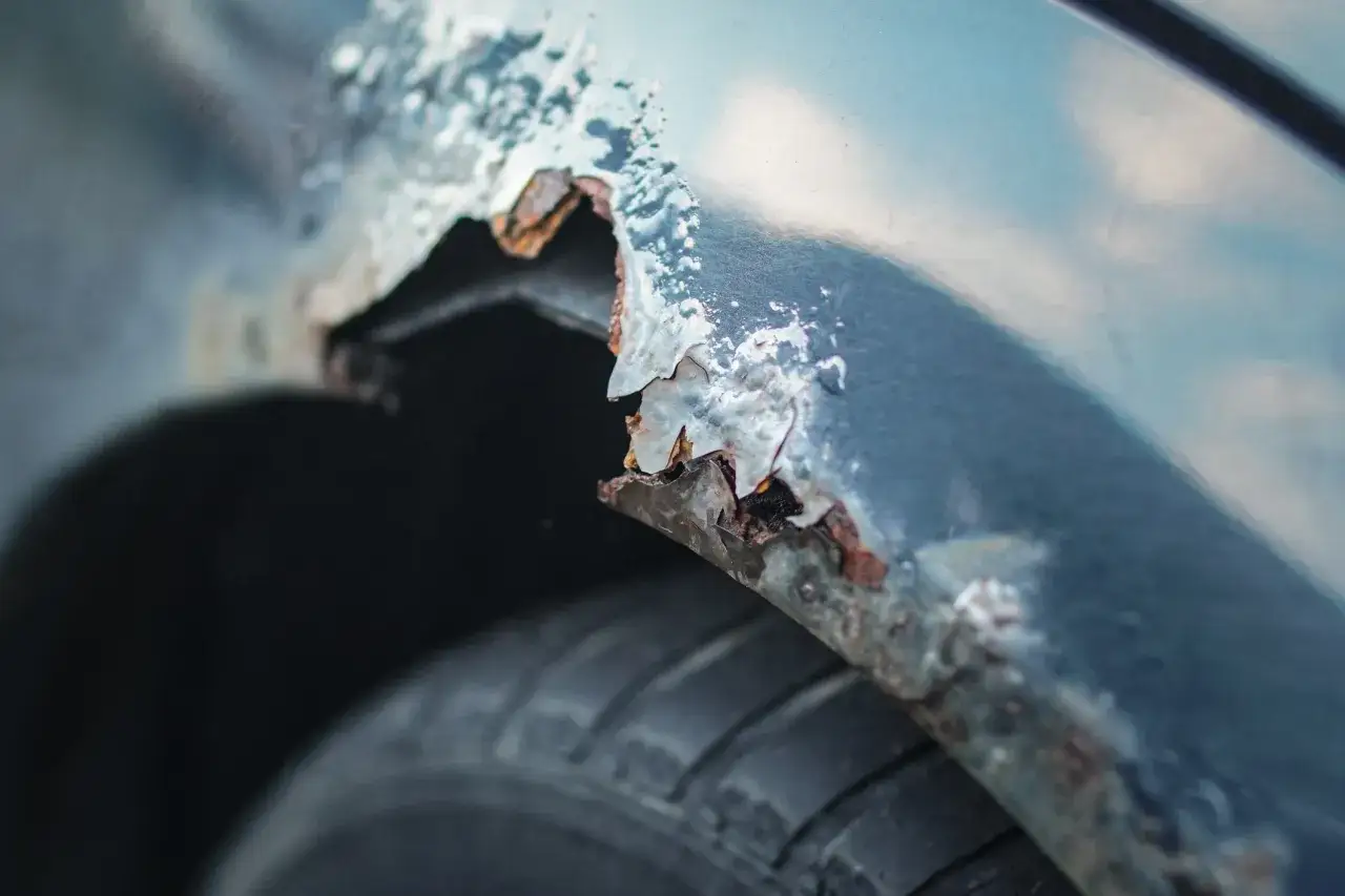 Detaljerad bild av en bilskärm med kraftig rost. Det är dags att slipa rost och fixa bilen.