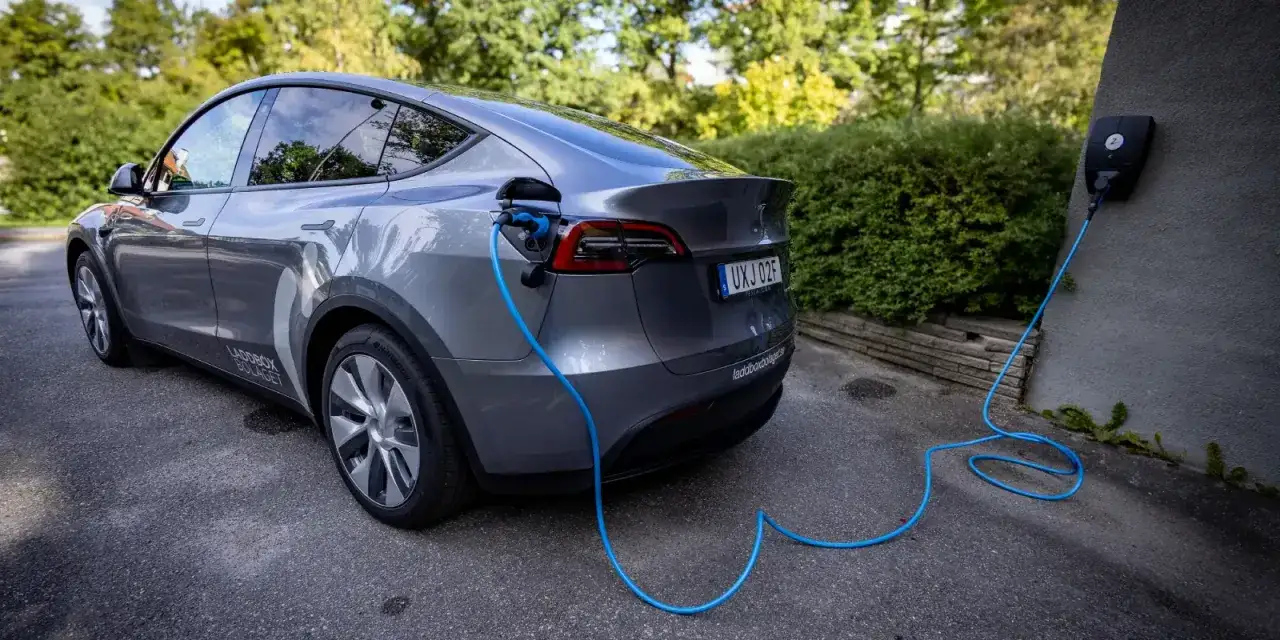Grå laddhybrid kopplad till laddbox. En laddhybrid är en skatt för miljön och plånboken.