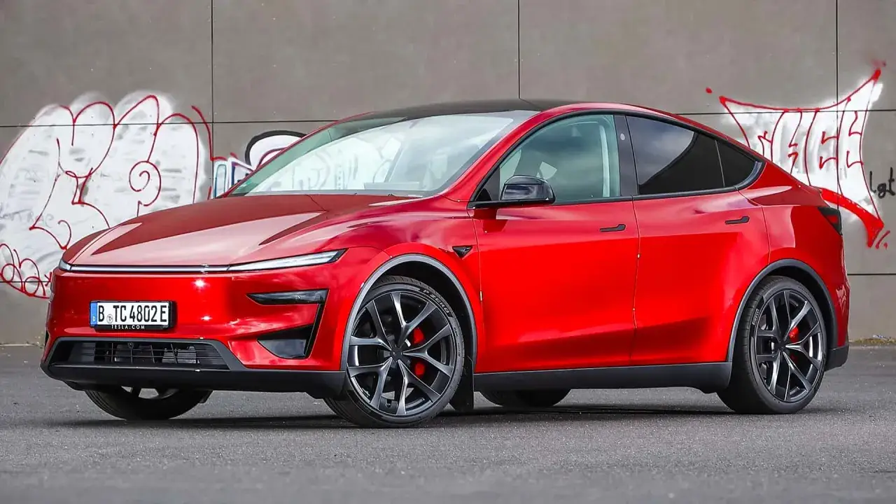 En r&ouml;d Tesla Model Y Performance st&aring;r framf&ouml;r en v&auml;gg med graffiti. Bilen har svarta f&auml;lgar och r&ouml;da bromsok.