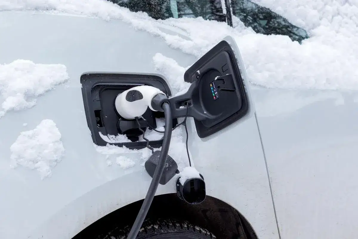 En elbil laddas i snöigt vinterväder.