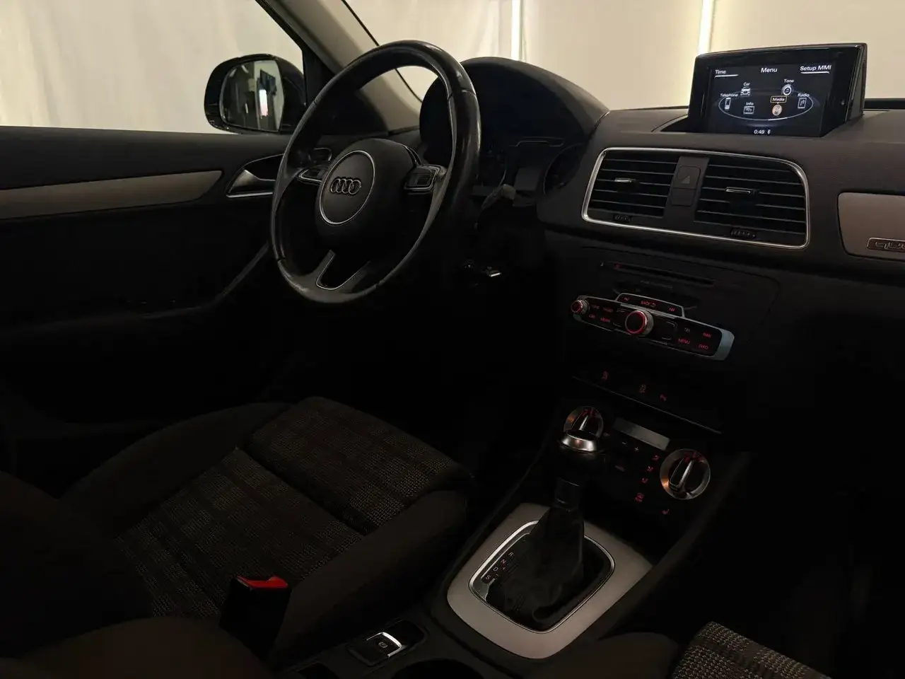 Interiörbild av en Audi Q3. Ratt, växellåda och infotainmentsystem syns. Kanske ett audi q3 problem med skärmen?