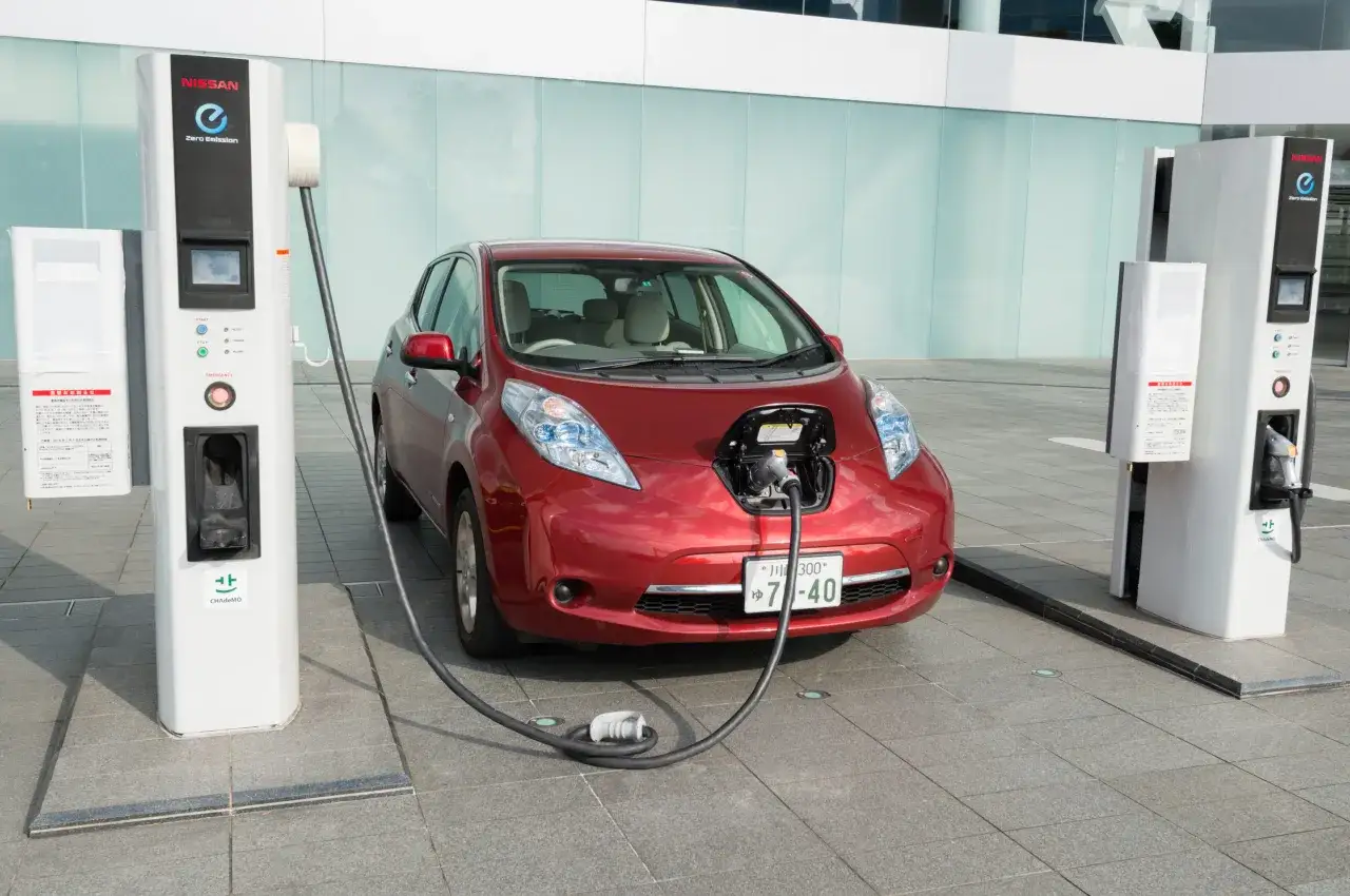 Röd Nissan Leaf 62 kWh laddas vid en laddstation.