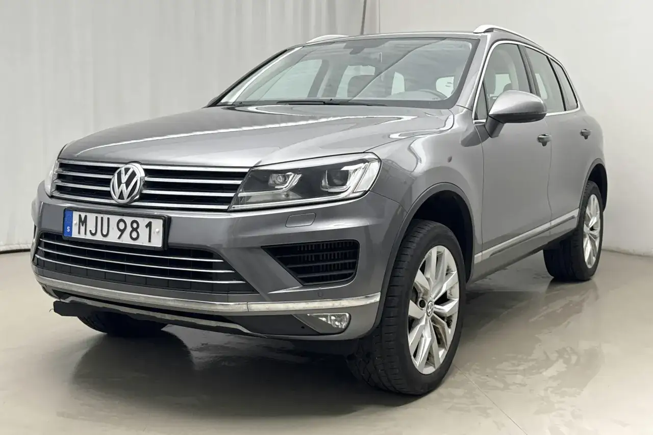 Grå VW Touareg med registreringsskylten MJU 981. En liten del av underredet verkar hänga löst, vilket kan vara ett vw touareg problem.