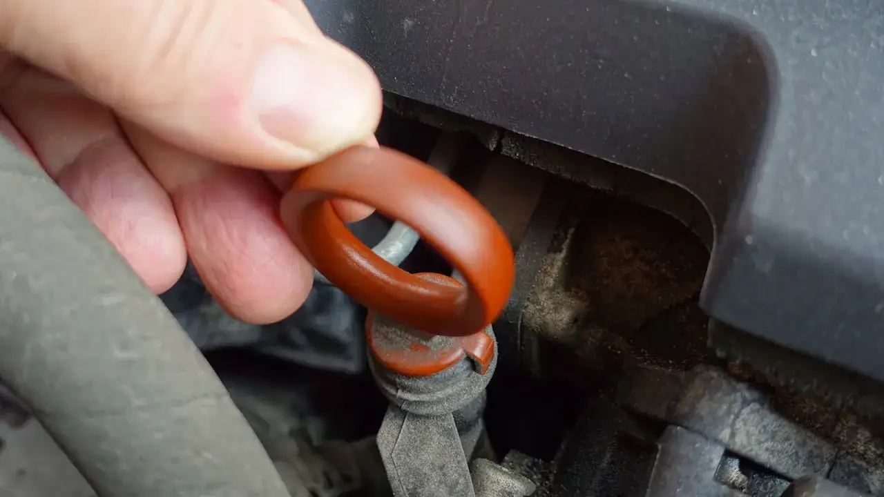 En hand drar i oljestickans orange ring. Kontrollera oljeniv&aring;n regelbundet f&ouml;r att veta hur ofta ska man fylla p&aring; olja i bilen.