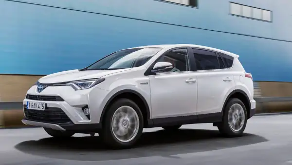 Vit Toyota RAV4 Hybrid körs på vägen, kanske med ett **toyota rav4 automat problem** som behöver åtgärdas.