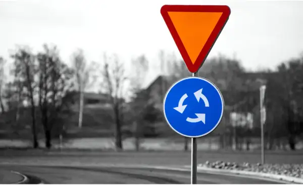 Varningsskylt för cirkulationsplats och väjningsplikt. Viktiga trafikregler frågor för säker körning.