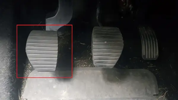 Kopplingspedalen i en manuell bil, markerad med röd ram. Denna pedal är avgörande för att växla.