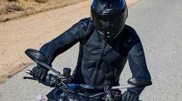 Motorcyklist i en Alpinestars skinnjacka, redo för äventyr på en öppen väg.