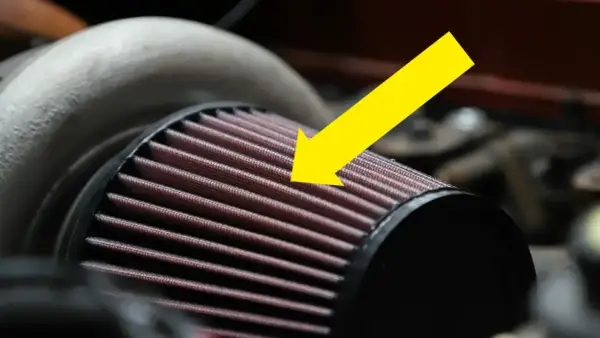 En gul pil pekar på det röda luftfiltermaterialet på ett bilfilter.