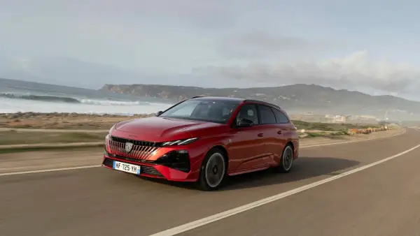Röd Peugeot 308 kombi kör längs en kustväg. Inga problem med denna bil, bara en vacker vy.